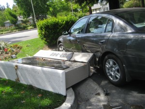 The complex\'s entrance sign crashed into the side of a parked car. 